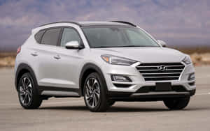 白色現代 Tucson SUV 停泊在戶外，靠近山脈，天空多雲 — Steam Deck 壁紙