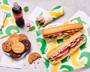 Subway三文治、曲奇餅和可口可樂放在品牌紙上。