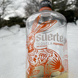 雪地冬季環境中帶有橙色兔子圖案的龍舌蘭酒瓶。