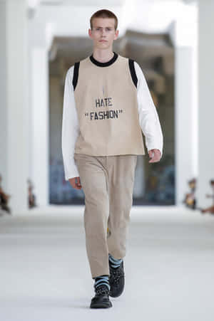 男模特兒身穿印有「I HATE FASHION」字樣的米色背心在T台上走秀。