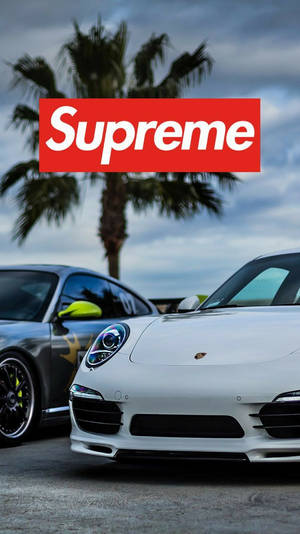 白色和灰色的跑車停泊在棕櫚樹下，並帶有Supreme標誌疊加。