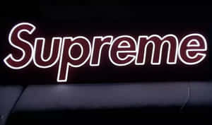 霓虹燈 Supreme 標誌在黑色沙發上方的黑暗牆壁上發光。