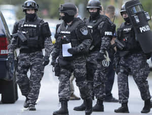 身穿戰術裝備的警察沿著街道行走。