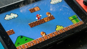 一個手提遊戲裝置顯示經典瑪利歐遊戲，像素化圖形，屏幕上可見灰塵。