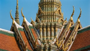 藍天下泰國寺廟的金色尖頂和彩色瓦頂。
