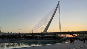 現代斜拉橋橫跨水面，日落時有人行走