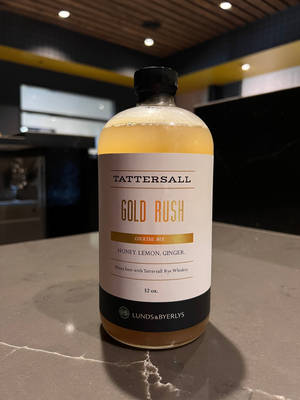 現代酒吧大理石檯面上的一瓶 Tattersall Gold Rush 雞尾酒調配液。