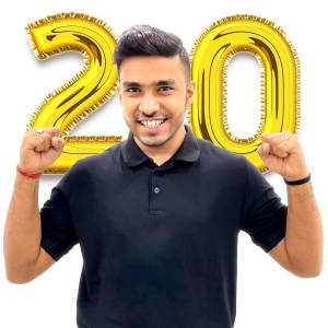 男人在金色20氣球後舉起拳頭慶祝。