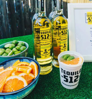 Tequila 512瓶子與青檸和橙片在綠色草地上。