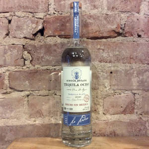 木頭上的Tequila Ocho酒瓶與磚牆。