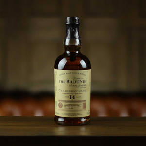 一瓶 The Balvenie 14 年 Caribbean Cask 威士忌放在木桌上。