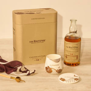 木桌上的 Balvenie 威士忌套裝，包括瓶子、盒子、杯子和絲巾。