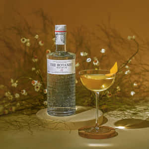 一瓶 The Botanist 氈酒和一杯橙裝飾雞尾酒，放在木杯墊上，伴有乾花。