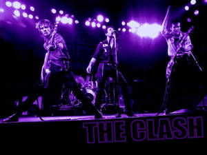 The Clash 樂隊在紫色燈光下於舞台上現場表演。