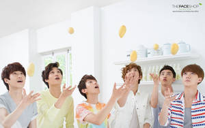 五位年輕男子在白色房間中接住飄浮的芒果。