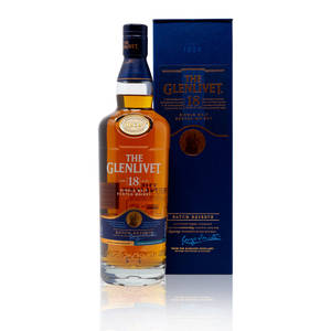 一瓶 Glenlivet 18 年威士忌及其藍色盒子放在反光表面上。
