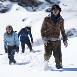 三個人穿著冬季裝備和太陽眼鏡，在雪地山區地形中徒步。 — 雪 壁紙