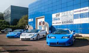 三輛Bugatti EB110超級跑車停在一棟帶有贊助商標誌的藍色玻璃建築前。 — 布加迪 壁紙
