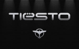 Tiesto 標誌，帶有翼形徽章，位於穿孔金屬背景上，配有聚光燈。