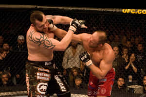 兩名MMA拳手在UFC八角籠內激烈纏鬥，觀眾在旁觀看。 — 搏擊會 GIF 壁紙