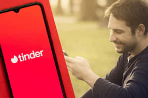 男士在戶外使用手機上的Tinder應用程式時微笑。