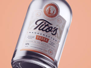 Tito's Handcrafted Vodka酒瓶，標籤細節在蜜桃色背景上