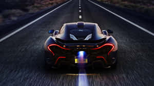 黑色McLaren跑車在黃昏時分在沙漠高速公路上飛馳，帶有發光的燈光。 — 麥拿侖 GIF 壁紙