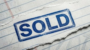 藍色「SOLD」印章在撕破的橫線筆記本紙上