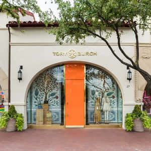 Tory Burch商店，橙色門和裝飾瓷磚窗，位於樹枝下。