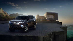 黑色豐田 Fortuner SUV 停泊在懸崖上俯瞰海洋，黃昏時分