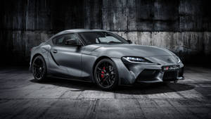 啞光灰色豐田GR Supra，紅色制動器，停在混凝土車庫中。