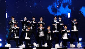 K-pop團體穿著黑白服裝在星光舞台上跳舞。