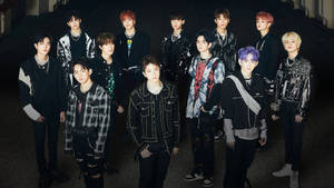 K-pop 團體在黑暗的城市小巷中擺姿勢，擁有色彩繽紛的頭髮和時尚服裝。