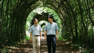 兩名男子在公園的茂密綠色藤架隧道下一起行走