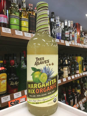 酒舖貨架上的一瓶 Tres Agaves Margarita Mix Organic 與其他酒瓶。 — 3:4 壁紙
