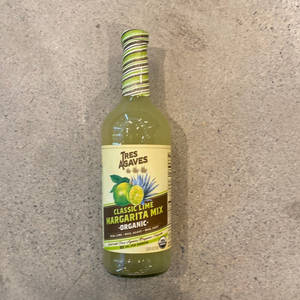 一瓶有機青檸瑪格麗特混合飲料喺灰色枱面上。