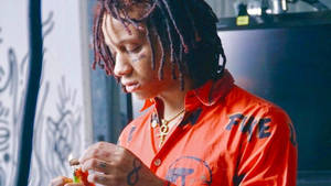 紅色辮子頭的年輕男子在室內塗鴉牆附近點燃香煙。 — Trippie redd GIF 壁紙