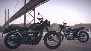 兩輛復古Triumph電單車在日落時停泊在橋附近。