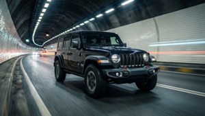 黑色Jeep Wrangler在明亮的隧道中快速行駛，帶有模糊的運動軌跡。