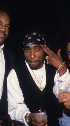 Tupac Shakur 在夜間派對上戴著金飾做出和平手勢。