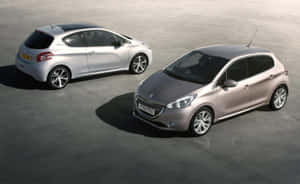 兩輛現代Peugeot 208掀背車，銀色和玫瑰金色，停在混凝土上。 — Steam Deck 壁紙