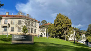 Rausser College of Natural Resources 標誌，學生在長滿草的大學山坡上行走。