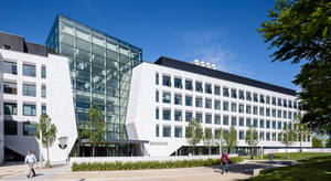 現代大學建築，玻璃外牆，人們在校園小路上行走。