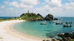 海灣，船隻停泊在岩石海岸附近，燈塔在長滿青草的海岬上