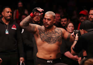 有紋身的MMA拳手在擠滿觀眾的場館中慶祝勝利。