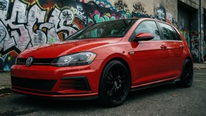 紅色福士Golf R，黑色輪圈，停在塗鴉牆前。