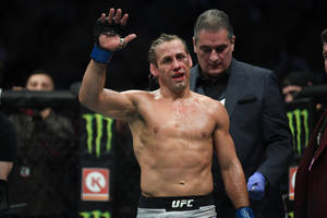 一名滿臉鮮血的勝利MMA拳手在UFC八角籠內向人群揮手。