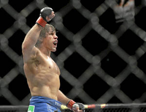 一位赤裸上身的MMA戰士在八角籠內高舉拳頭慶祝勝利。