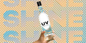 手拎住UV伏特加酒瓶，背景係彩色幾何圖案同'SHINE'字樣。
