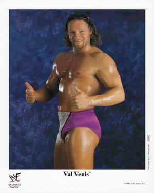 摔角手 Val Venis 穿著紫色短褲，在藍色背景前豎起雙拇指。